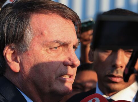 Esta é um close-up lateral do ex-presidente brasileiro Jair Bolsonaro em um ambiente externo, provavelmente falando ou respondendo a jornalistas.