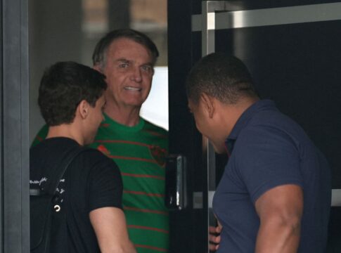 Imagem mostra o ex-presidente Jair Bolsonaro recebendo o deputado Nikolas Ferreira, que está de costas e com camisa preta. Ao lado, aparece um homem de camisa azul.