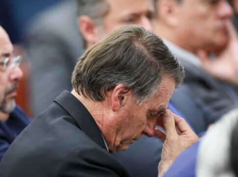 Imagem mostra o ex-presidente Jair Bolsonaro pensativo com a cabeça baixa e mão sobre a testa.