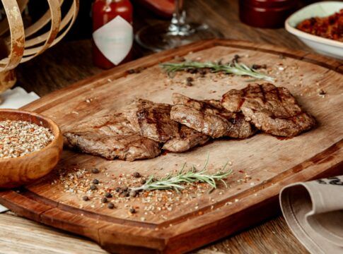 Imagem ilustrativa de carne frita em uma placa de madeira