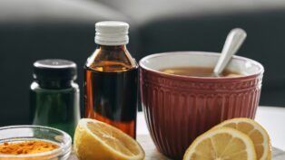 Em imagem ilustrativa, alguns fracos de medicamentos, chás e limões cortados estão sob a mesa