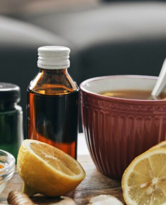 Em imagem ilustrativa, alguns fracos de medicamentos, chás e limões cortados estão sob a mesa