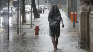 Uma pessoa caminha na calçada em meio a fortes chuvas no Brasil