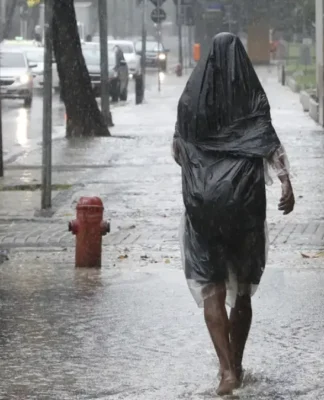 Uma pessoa caminha na calçada em meio a fortes chuvas no Brasil