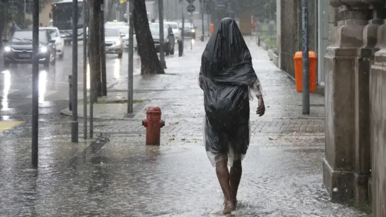 Uma pessoa caminha na calçada em meio a fortes chuvas no Brasil