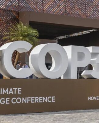 Imagem mostra o letreiro da COP30, em Belém, com fonte branca sobre uma bancada marrom.