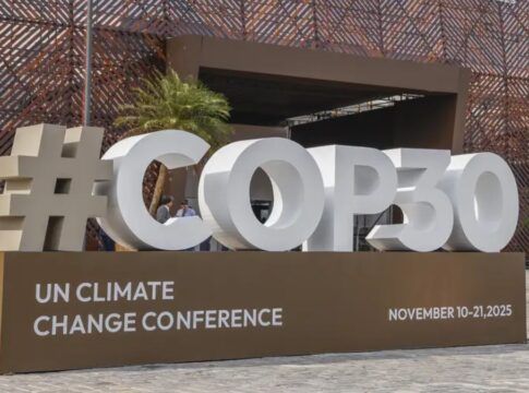 Imagem mostra o letreiro da COP30, em Belém, com fonte branca sobre uma bancada marrom.