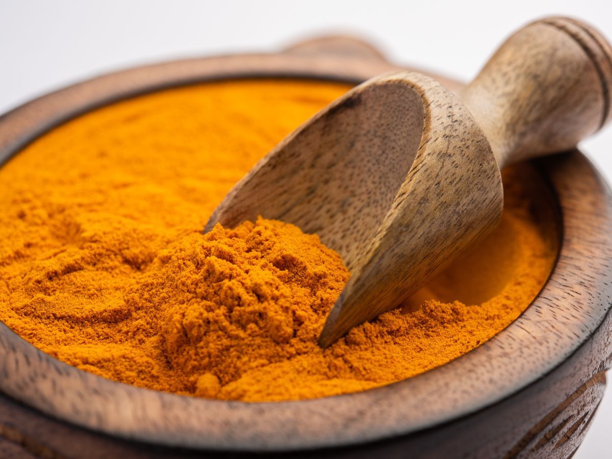 a imagem mostra o tempero cúrcuma dentro de um recipiente de madeira