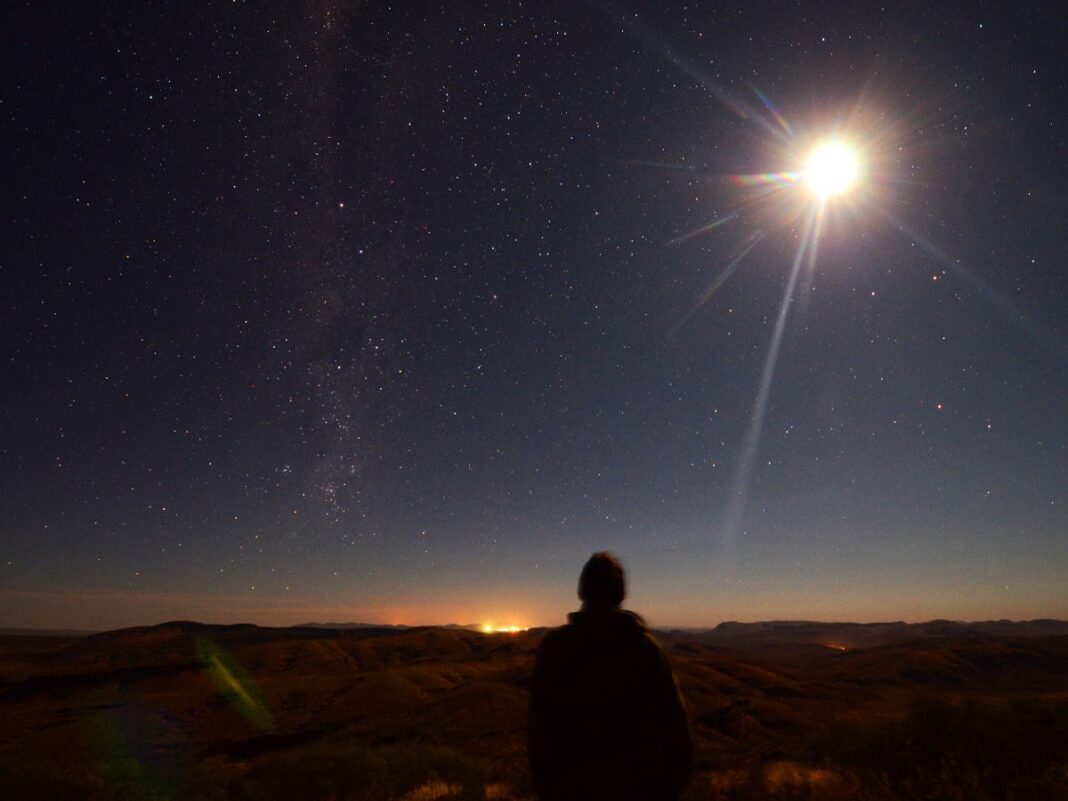 Em imagem ilustrativa, pessoa observa um eclipse se formando