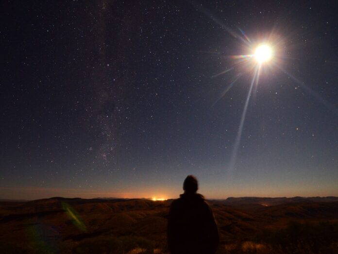 Em imagem ilustrativa, pessoa observa um eclipse se formando