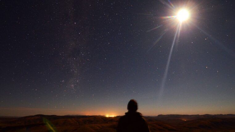 Em imagem ilustrativa, pessoa observa um eclipse se formando