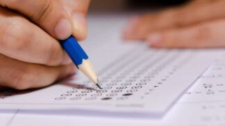 Em imagem ilustrativa, jovem completa gabarito de prova.