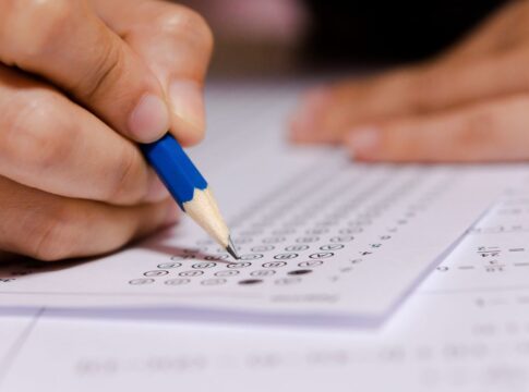 Em imagem ilustrativa, jovem completa gabarito de prova.