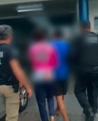 Imagem mostra a prisão de dois homens. Os rostos deles estão desfocados. Dois policiais os acompanham.