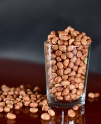 E imagem ilustrativa, há um copo estilo americano com feijões dentro e grãos caídos a mesa.