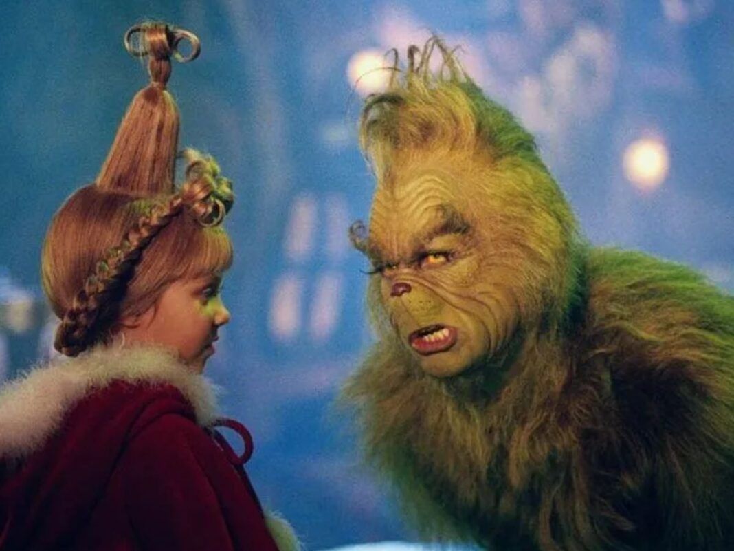 Na foto há um homem pintado de verde e com pelos colados no corpo. Há também uma menina loiro com um penteado.