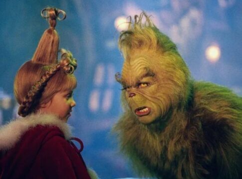 Na foto há um homem pintado de verde e com pelos colados no corpo. Há também uma menina loiro com um penteado.