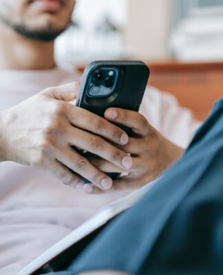 Imagem ilustrativa de um homem assistindo algo no celular