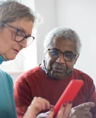 Em imagem ilustrativa, dois idosos consumindo produtos via celular