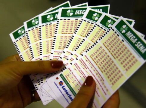 Pessoa segura em suas mãos cartões de apostas da Mega Sena