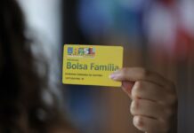 Em imagem ilustrativa, jovem segura o cartão do Bolsa Família