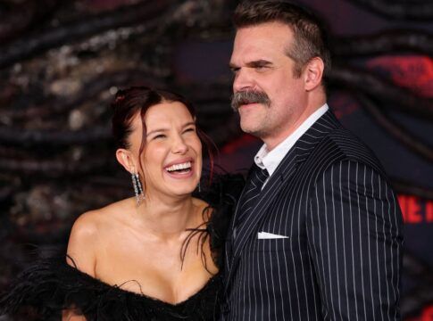 Imagem mostra os atores Millie Bob Brown e David Harbour abraçados e rindo durante o Stranger Things Day.