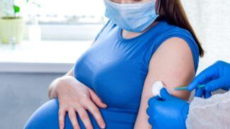 Em imagem ilustrativa, mulher gravida toma vacina