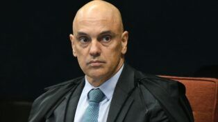 A foto é um retrato em plano médio-fechado, focado no Ministro do Supremo Tribunal Federal (STF), Alexandre de Moraes. O ministro aparece em uma pose formal, olhando diretamente para a frente ou ligeiramente para o lado direito do observador. Ele tem a cabeça raspada/calva e as sobrancelhas arqueadas, com uma expressão séria, tensa e de intensa concentração, que pode ser interpretada como desconfiança ou atenção plena. Seus olhos estão arregalados e fixos.