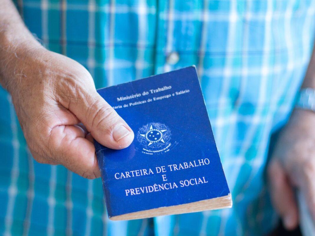 Em imagem ilustrativa, um idoso segurando em suas mãos uma carteira de trabalho.