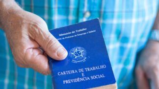 Em imagem ilustrativa, um idoso segurando em suas mãos uma carteira de trabalho.