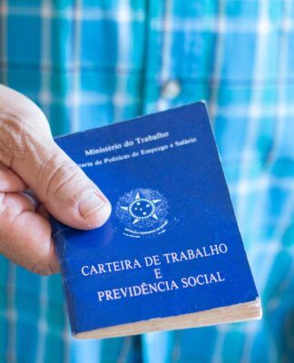 Em imagem ilustrativa, um idoso segurando em suas mãos uma carteira de trabalho.