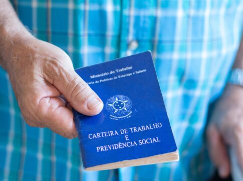 Em imagem ilustrativa, um idoso segurando em suas mãos uma carteira de trabalho.