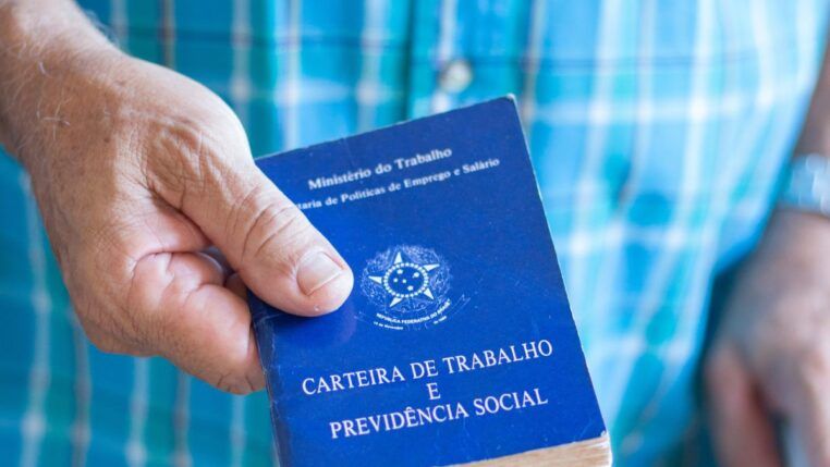 Em imagem ilustrativa, um idoso segurando em suas mãos uma carteira de trabalho.