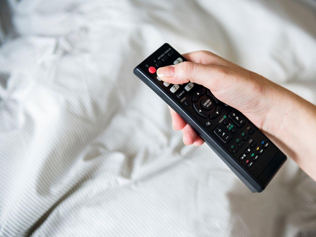 imagem mostra pessoa segurando um controle de televisão preto