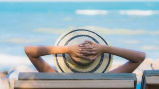 Homem na praia tomando um sol de chápeu