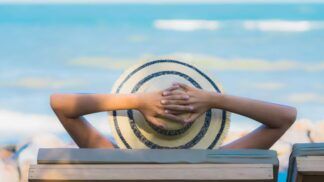 Homem na praia tomando um sol de chápeu