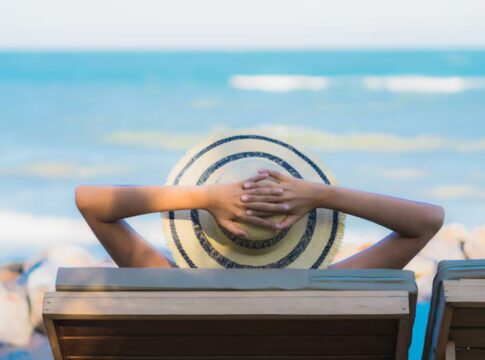 Homem na praia tomando um sol de chápeu