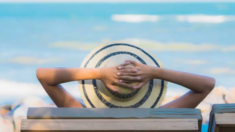 Homem na praia tomando um sol de chápeu
