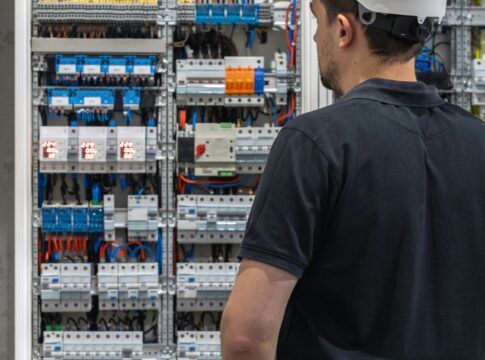 Em imagem ilustrativa, homem olha fixamente para painel elétrico.