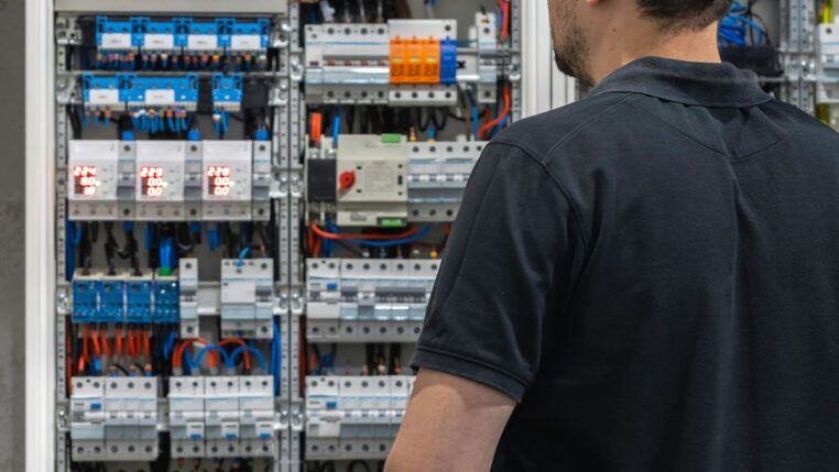 Em imagem ilustrativa, homem olha fixamente para painel elétrico.