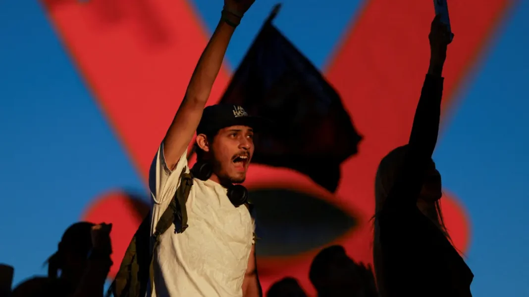 Um manifestante de punho erguido grita palavras de ordem no México, em protesto contra o governo local