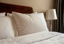 uma foto de uma cama com travesseiros bancos em cima