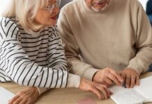 Em imagem ilustrativa, dois aposentados escrevendo em uma mesa