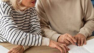 Em imagem ilustrativa, dois aposentados escrevendo em uma mesa