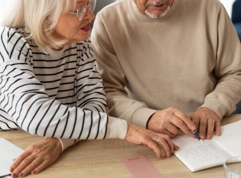 Em imagem ilustrativa, dois aposentados escrevendo em uma mesa
