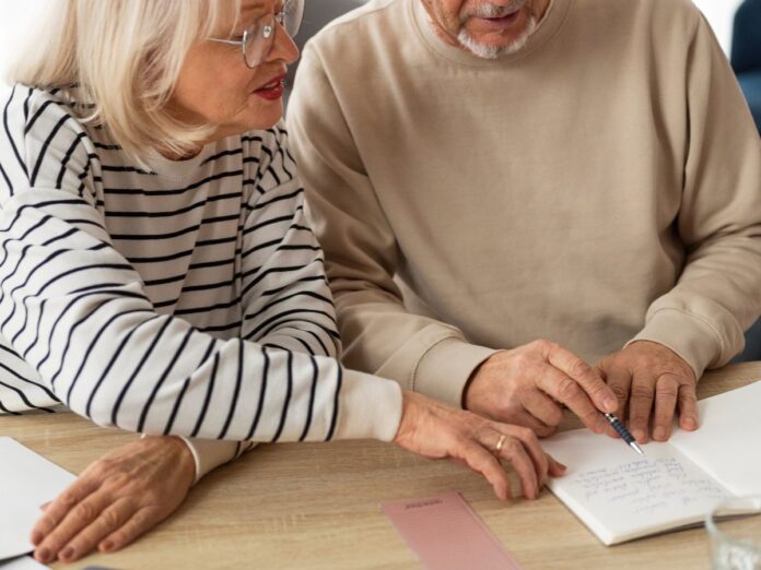 Em imagem ilustrativa, dois aposentados escrevendo em uma mesa