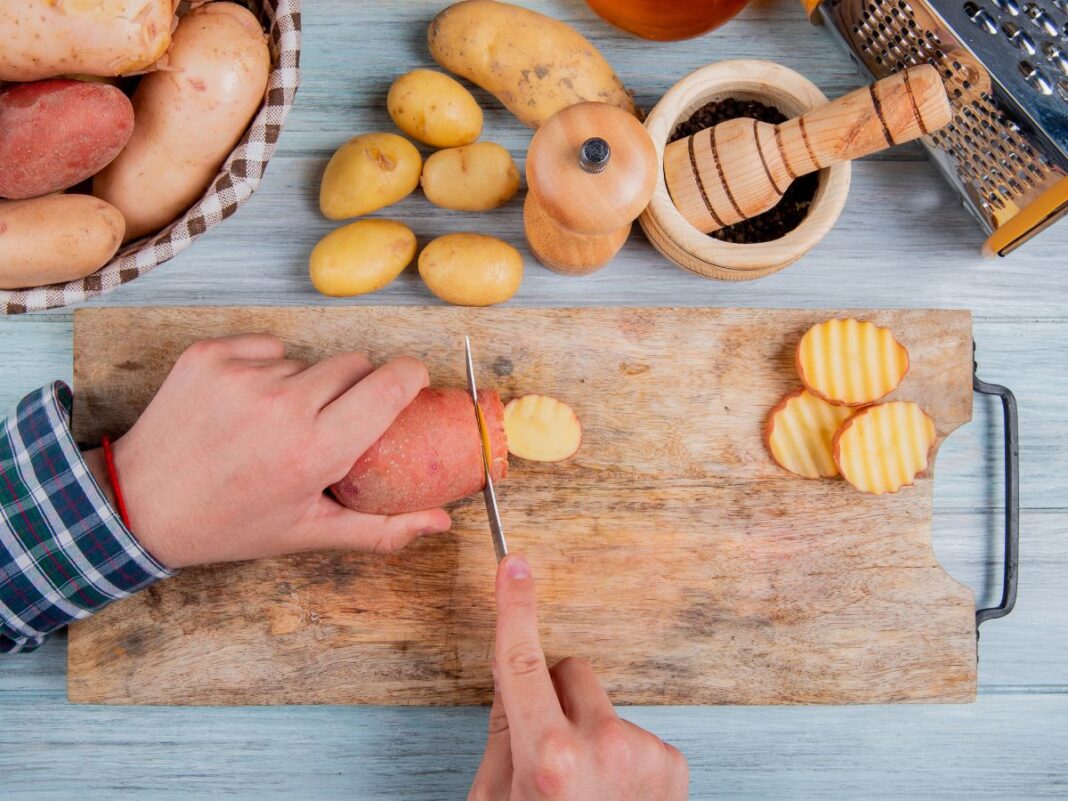 Em imagem ilustrativa, pessoas corta batatas doces para preparar o alimento
