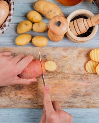 Em imagem ilustrativa, pessoas corta batatas doces para preparar o alimento