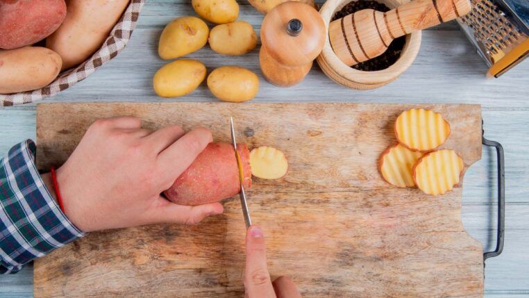Em imagem ilustrativa, pessoas corta batatas doces para preparar o alimento