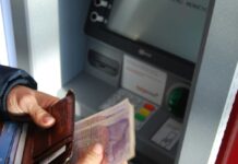 Em imagem ilustrativa, pessoa saca dinheiro em banco.